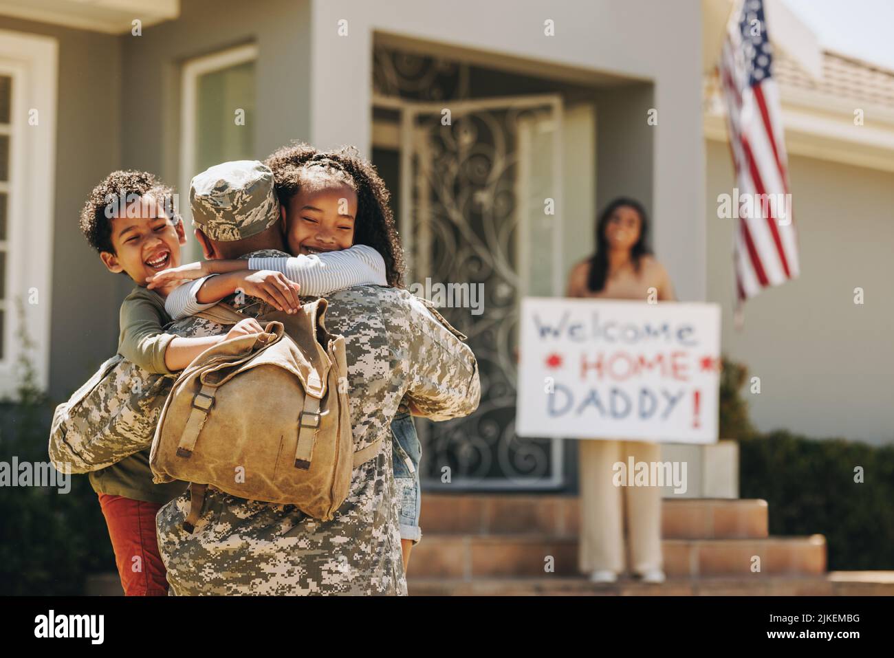 Cheerful children reuniting with their military dad. Two happy young children embracing their father upon his return from the army. American servicema Stock Photo