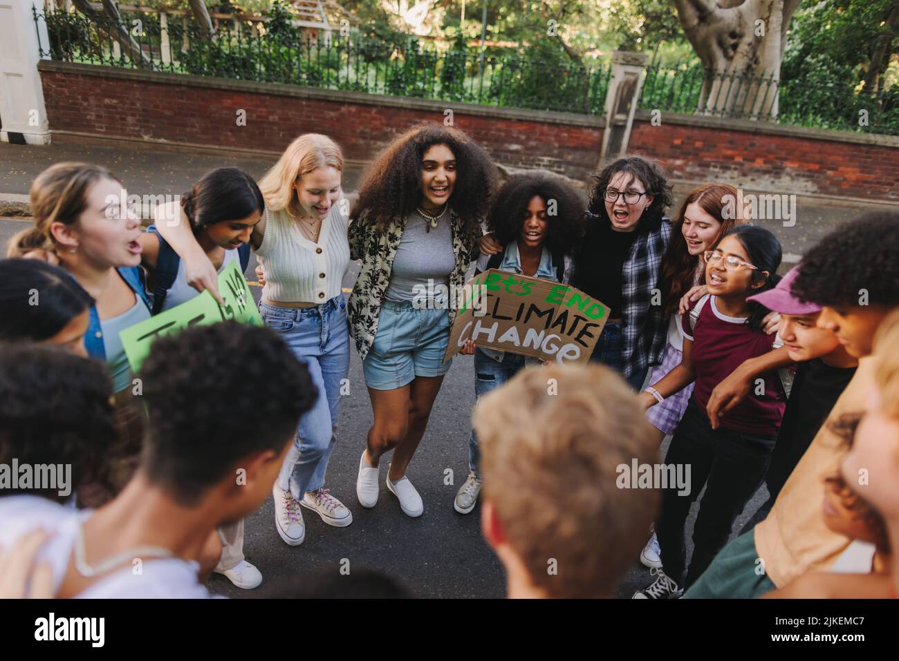 Uniting against climate change. Group of multicultural youth activists standing together in a circle at a climate protest. Generation Z youngsters joi Stock Photo