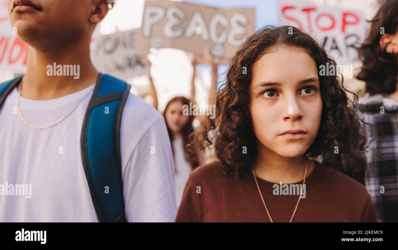 Generation Z peace march. Youth activists marching against war and violence in the streets. Group of protestors raising anti-war posters during a peac Stock Photo