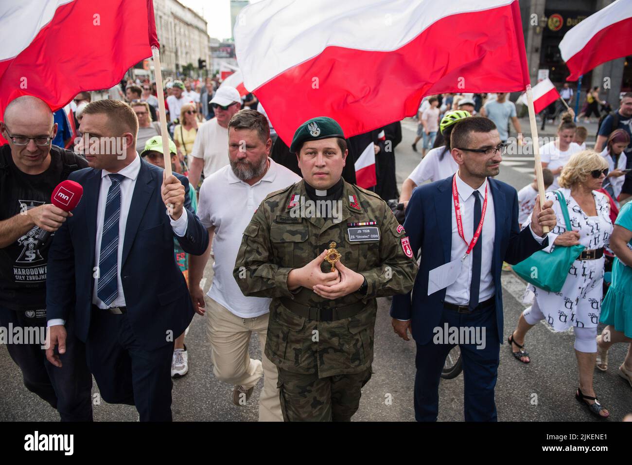 A priest in a military uniform walks in the crowd during the Warsaw ...