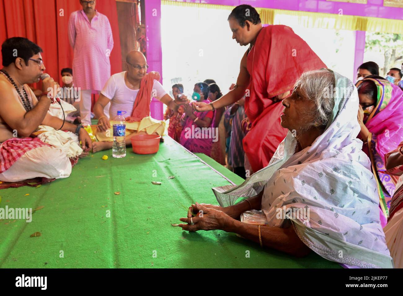 Howrah, West Bengal, India - 14th October 2021 : Senior aged Bengali widow worshipping Goddess Durga while Hindu Purohit uttering Sanskrit shlokas. Stock Photo