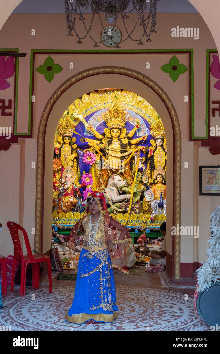 Howrah,India -October 26th,2020 : Bengali girl child posing with Goddess Durga in background, inside old age decorated home. Durga Puja festival. Stock Photo