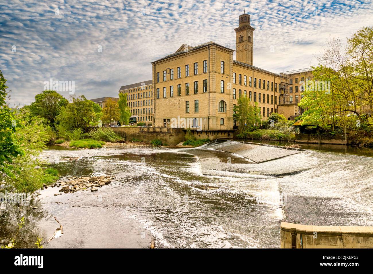 5 May 2022: Saltaire, Bradford, UK - Salt's Mill and the weir on the River Aire in spring. Stock Photo
