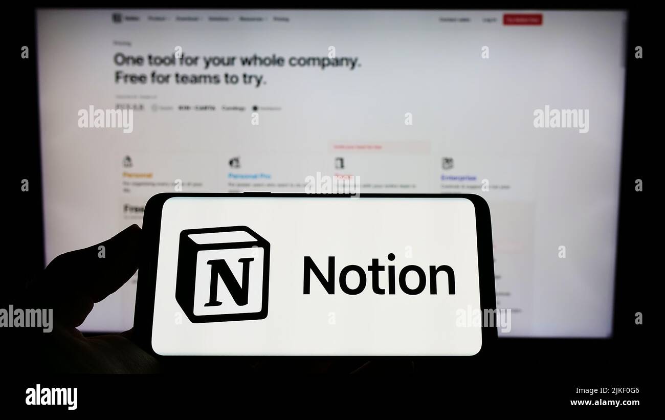 Person holding mobile phone with logo of American software company Notion Labs Inc. on screen in front of web page. Focus on phone display. Stock Photo
