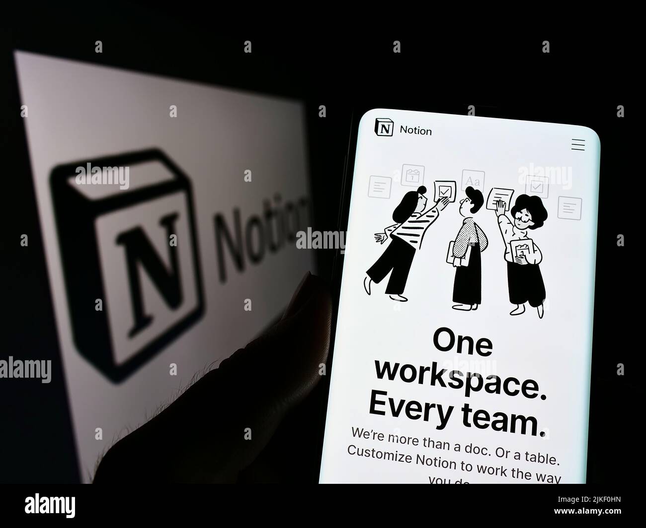 Person holding cellphone with webpage of US software company Notion Labs Inc. on screen in front of logo. Focus on center of phone display. Stock Photo