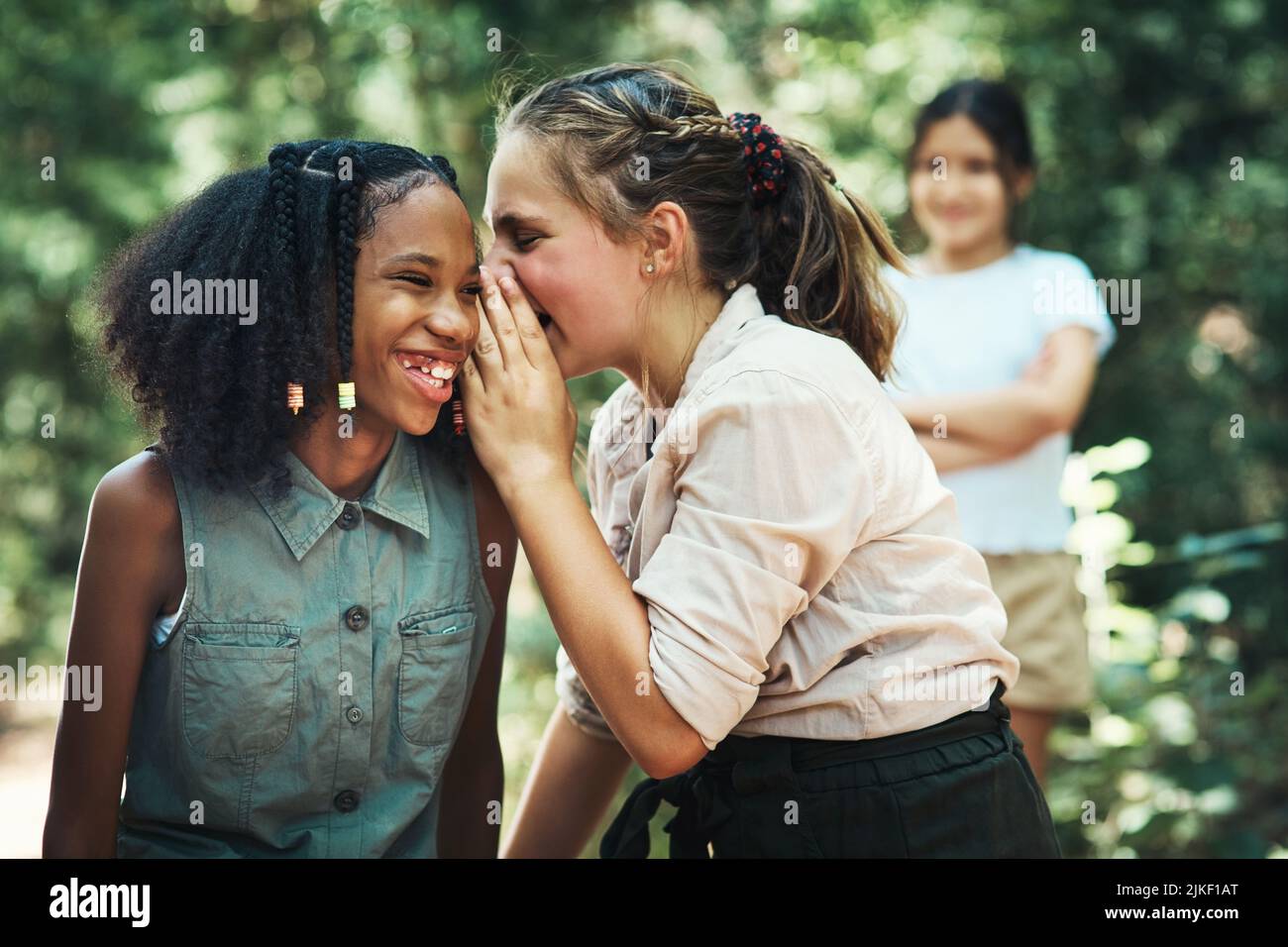 Beware the danger of bullying. two teenage girls gossiping about their friend at summer camp. Stock Photo