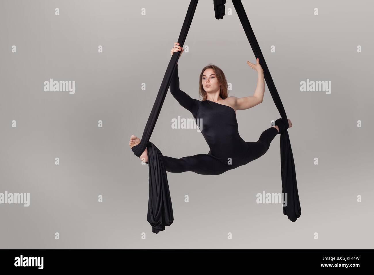 Beautiful girl in a black sport suit is performing an acrobatic ...