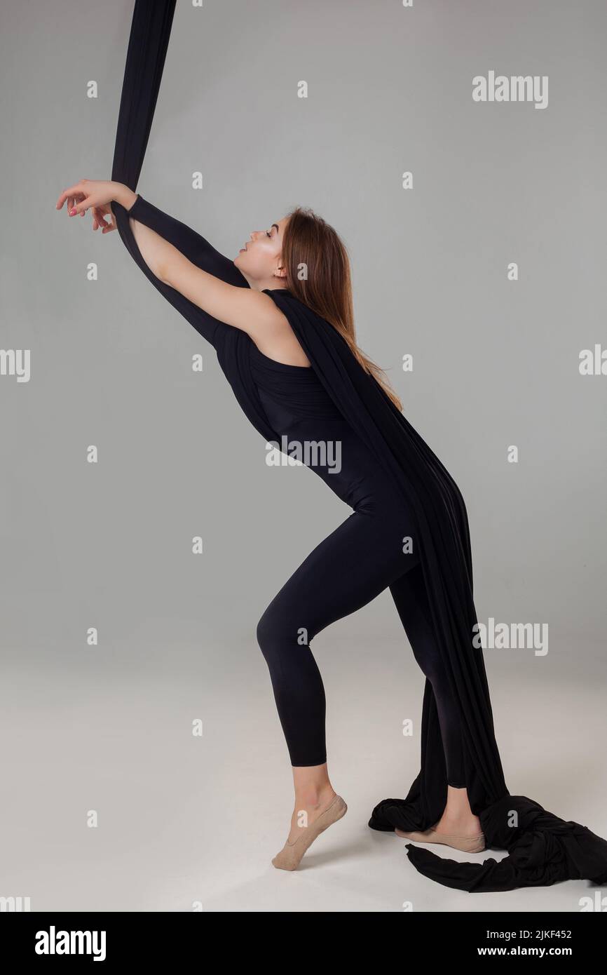 Beautiful girl in a black sport suit is performing an acrobatic ...