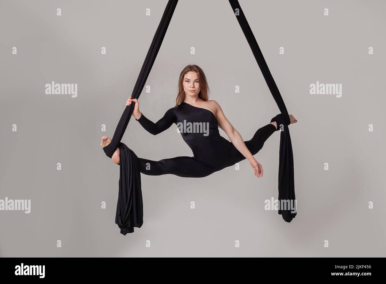 Beautiful girl in a black sport suit is performing an acrobatic ...
