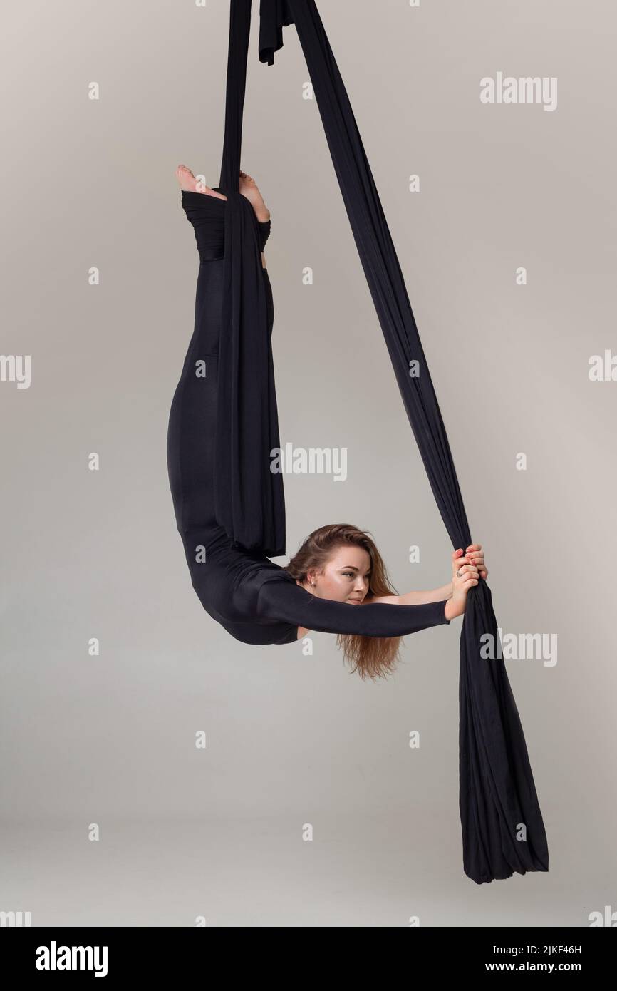 Beautiful girl in a black sport suit is performing an acrobatic ...