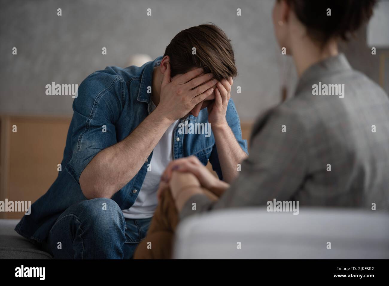 Psychologist talking with patient on therapy session. Depressed man speaking to a therapist while she is taking notes Stock Photo