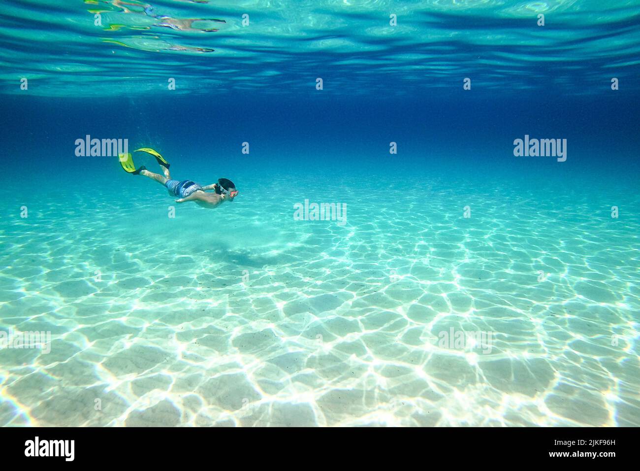 Underwater photo of a boy swimming with snorkeling fins and goggles on a beautiful Veli Zal beach, Dugi otok, Croatia Stock Photo
