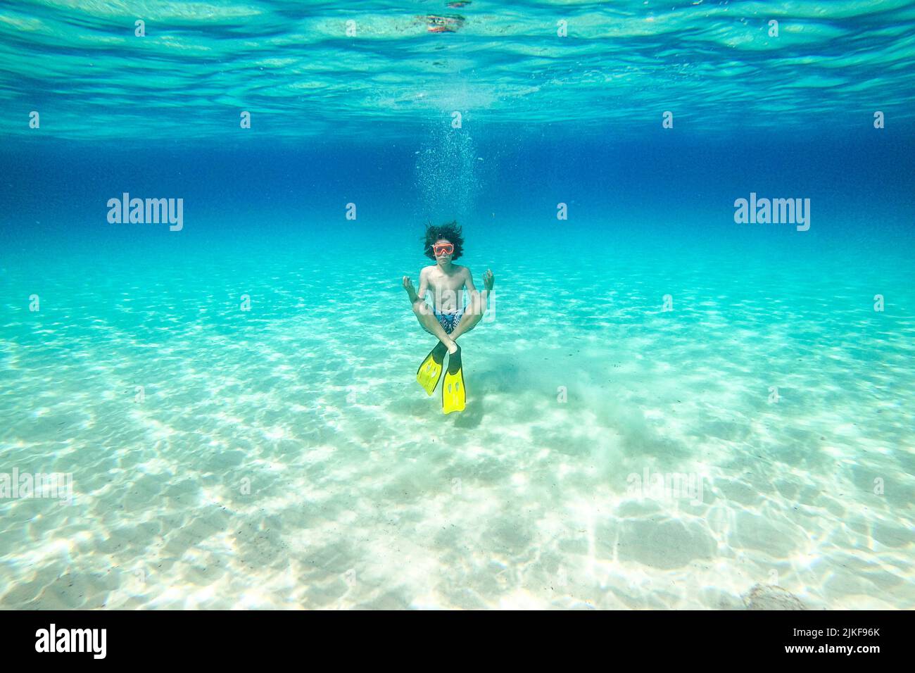 Underwater photo of a boy with snorkeling fins and goggles in yoga pose on a beautiful Veli Zal beach, Dugi otok, Croatia Stock Photo