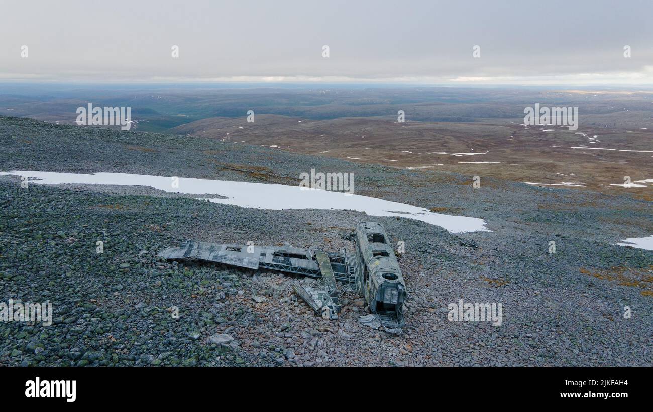 The black burnt-out vehicle parts in a field with small black rocks and scattered snow Stock Photo