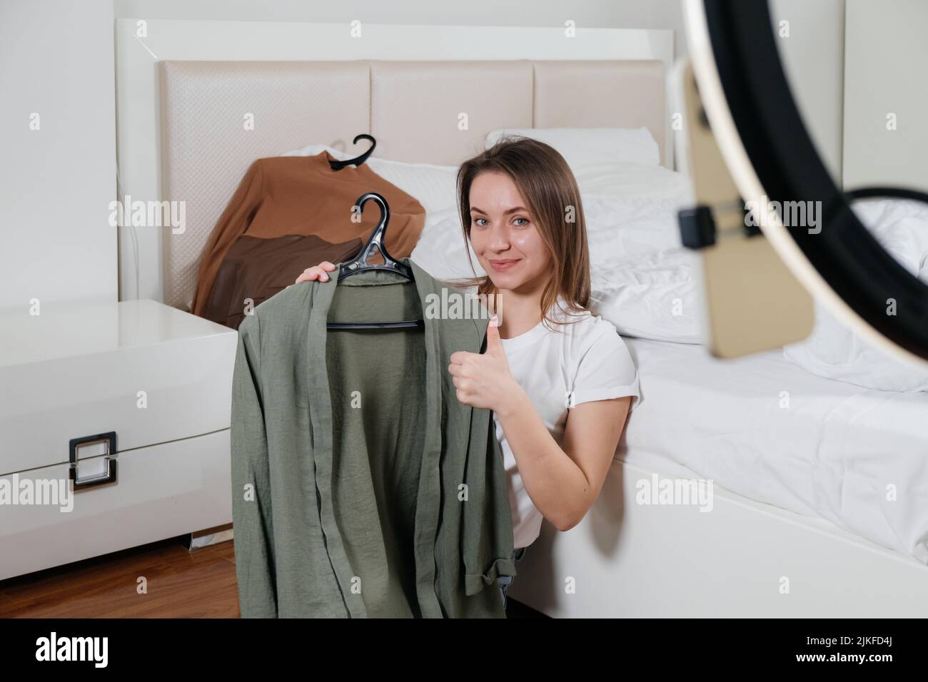 Female Blogger Recording Vlog Video on smartphone At Home Online Influencer On near bed choosing clothes, earthly look Stock Photo