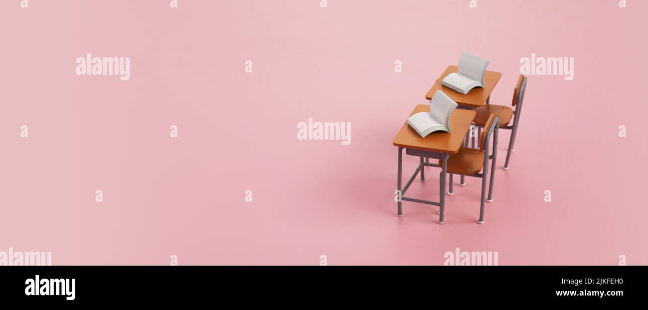 School desk with books on pink background. Stock Photo
