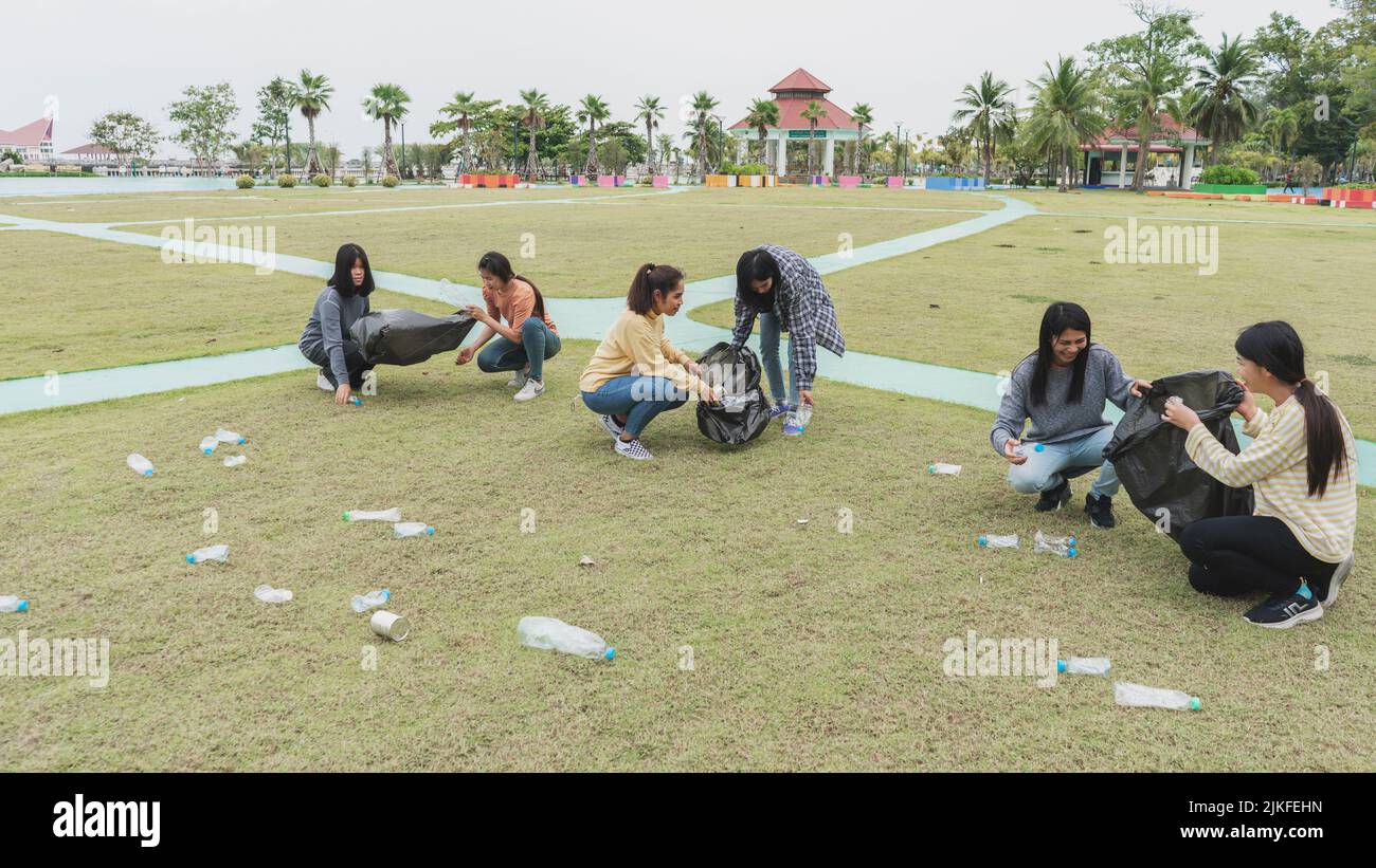 Asia Woman Group Team Volunteer picking up Trash plastics garbage plastic waste. Friend putting
