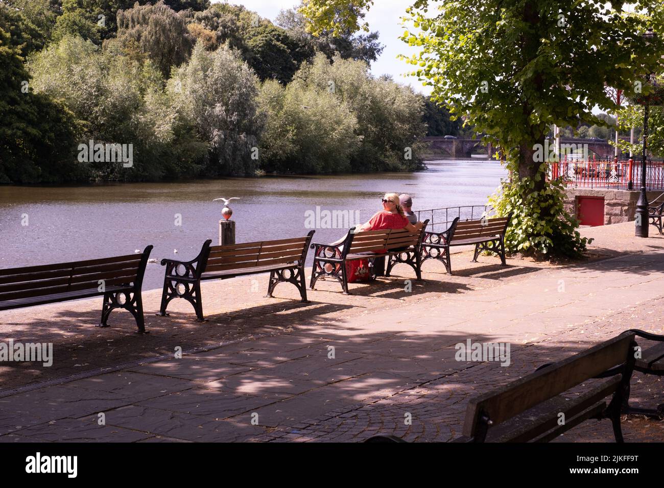 People relaxing on seats at The Groves on the River Dee at Chester, Chesire Stock Photo