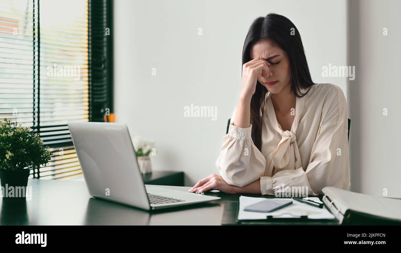 Overworked female entrepreneur massaging nose bridge, solving business
