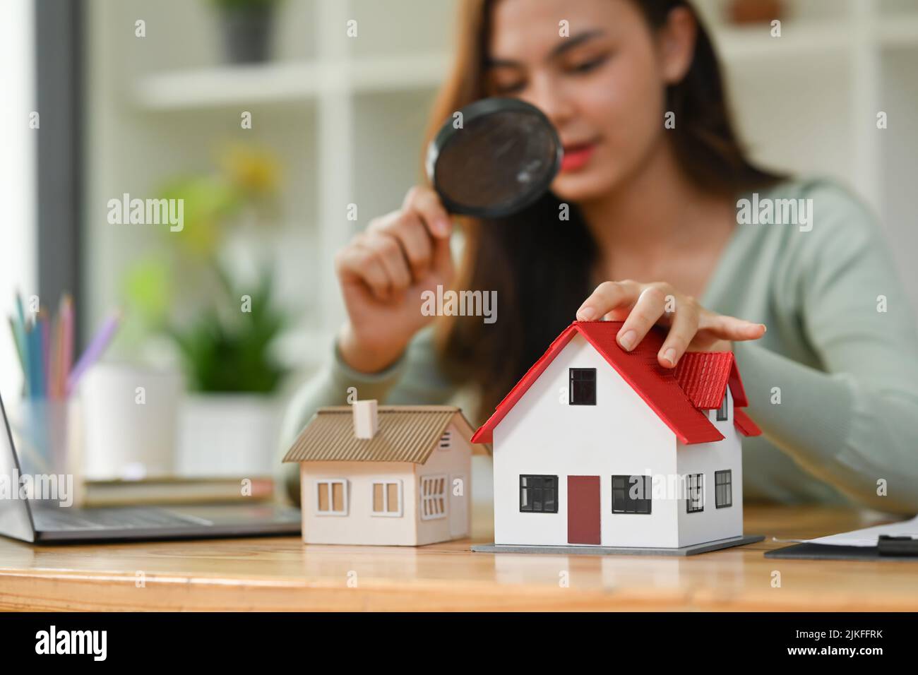Female appraiser looking at house model through magnifying glass. Real