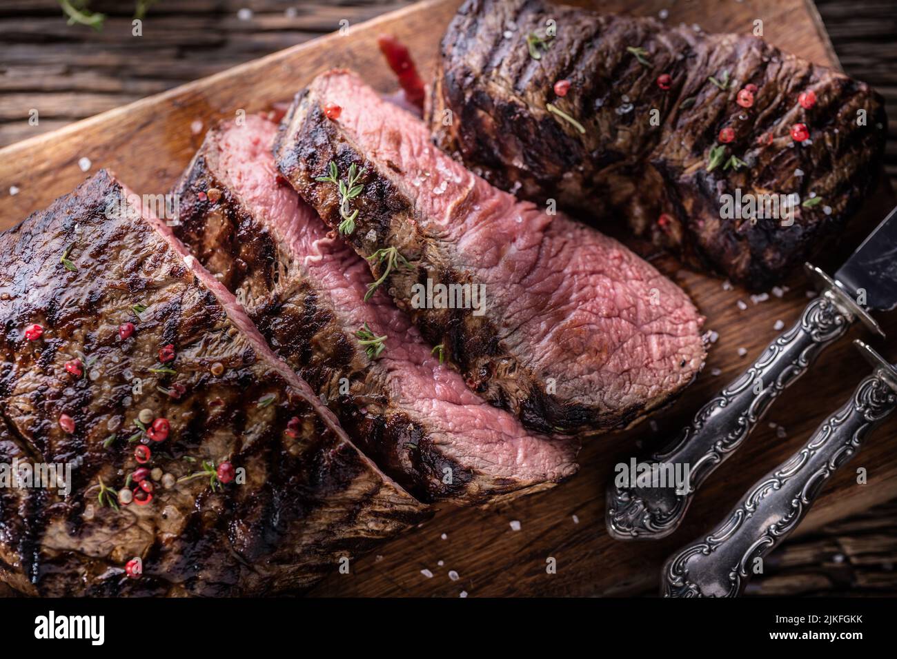 Grilled beef steak cut on a butcher board - Top of view. Stock Photo