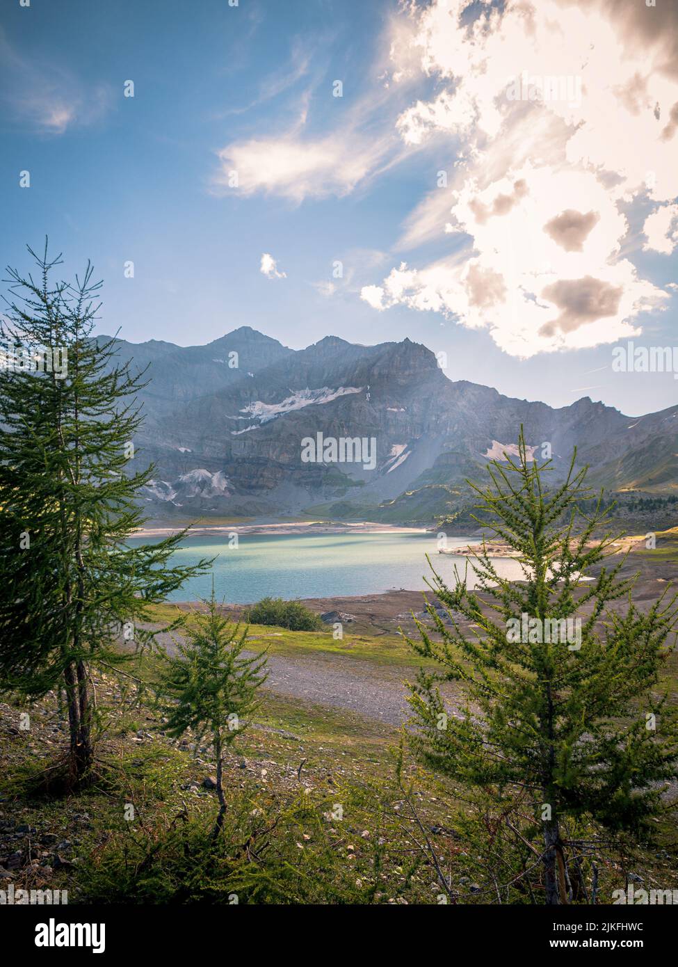Beautiful Alpine mountain valley. Pine trees line a steep mountain side and high peaks fade in the hazy distance. Stock Photo