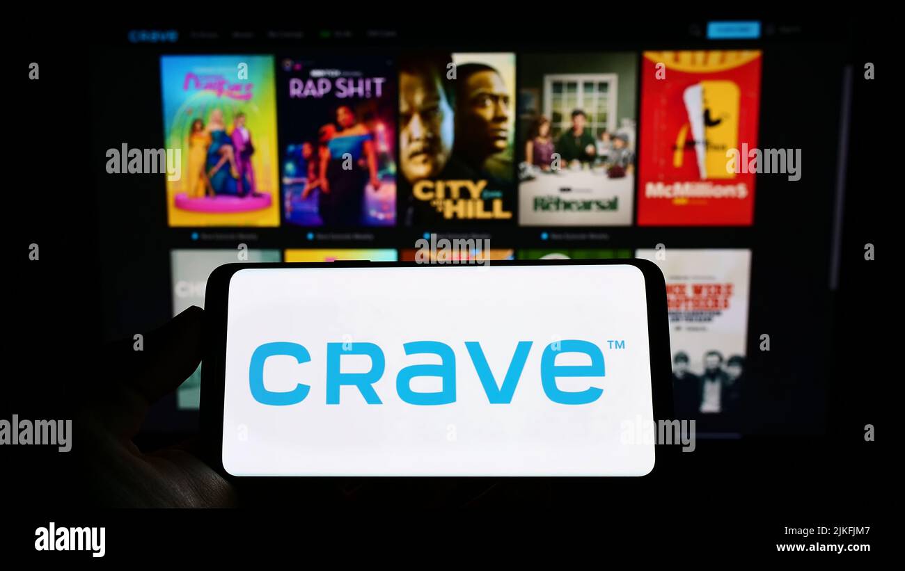 Person holding mobile phone with logo of Canadian video streaming company Crave on screen in front of business web page. Focus on phone display. Stock Photo