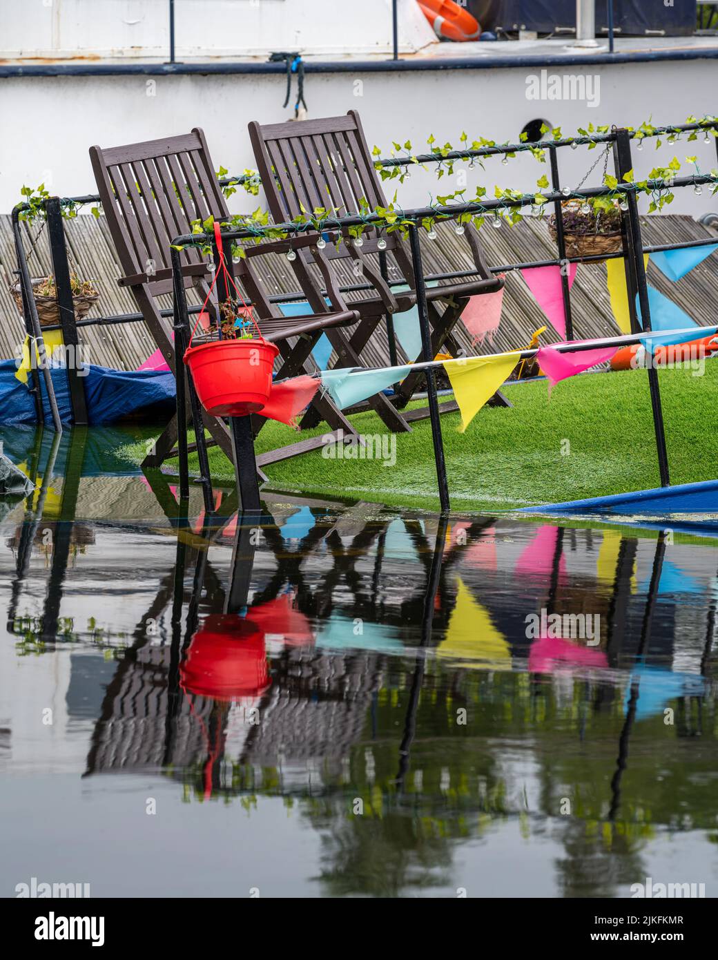 Neatly arranged deckchairs and bunting on a slowly sinking boat on the canal Stock Photo