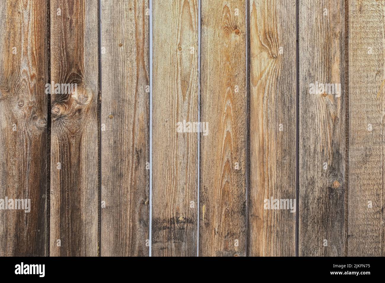 Threadbare clapboards texture. Old weathered wall of rustic barn covered with worn wooden planks for background.  Stock Photo