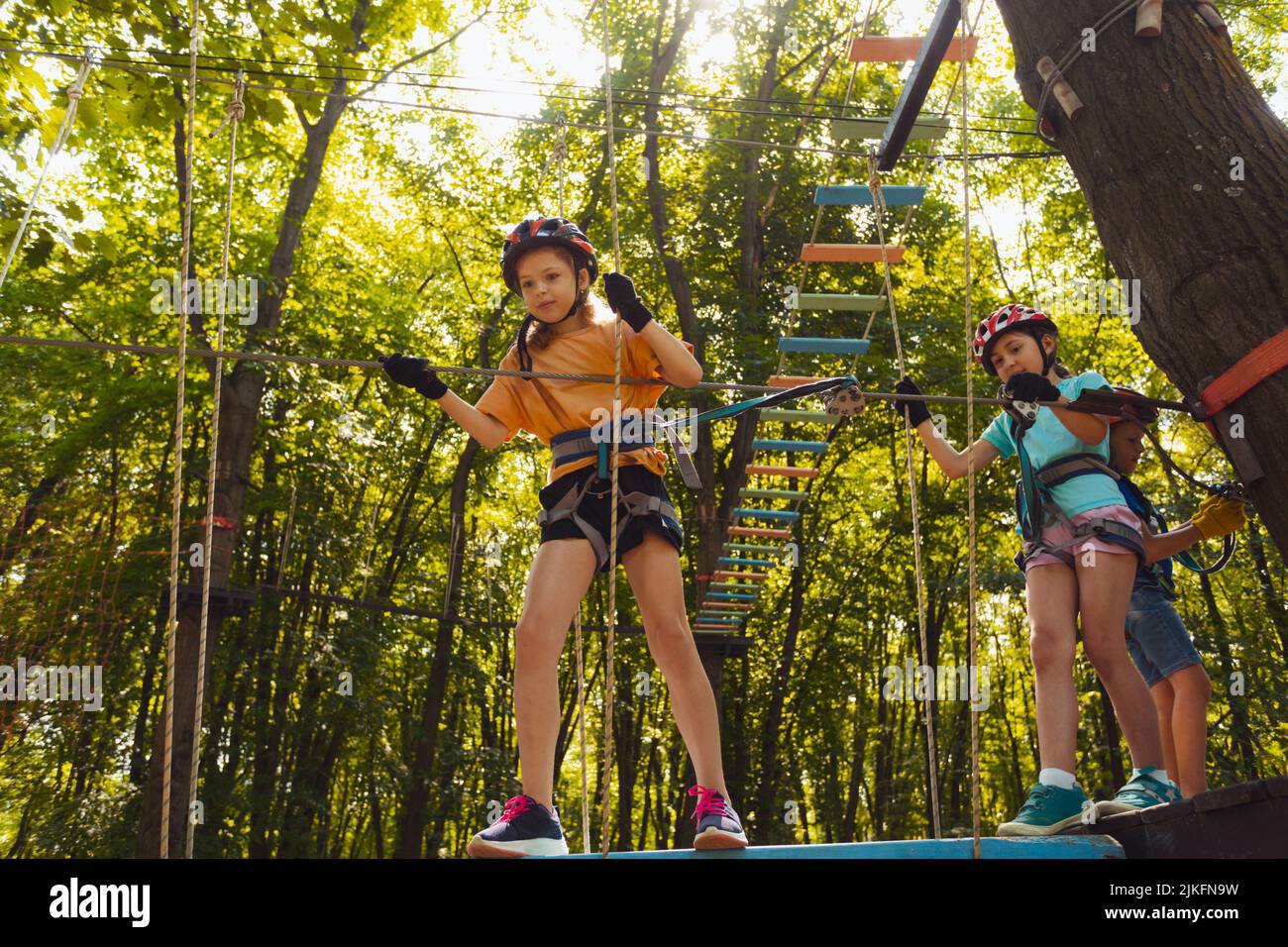 The concentrated kids are climbing in the high rope park Stock Photo