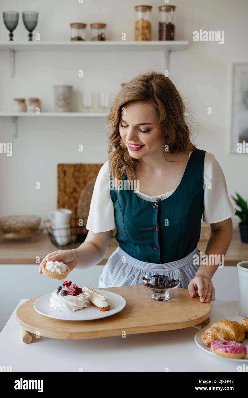 Girl shifts cakes on a dish in the kitchen Stock Photo