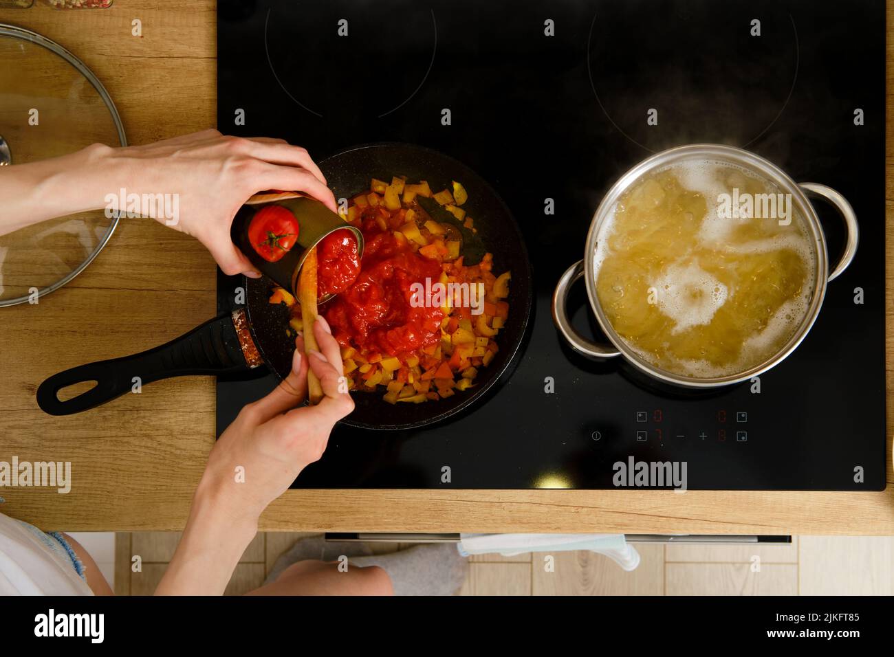 Closeup overhead view of female hand adding canned whole peeled ...