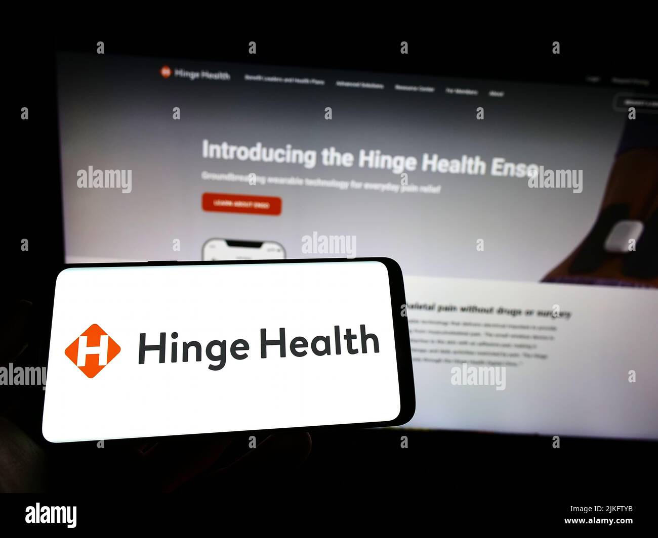 Person holding cellphone with logo of US digital clinic company Hinge Health Inc. on screen in front of business webpage. Focus on phone display. Stock Photo