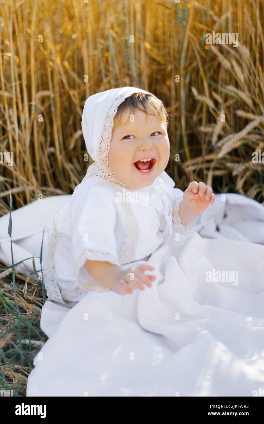 Sweet eightmonthold baby boy sitting on a blanket in a field and