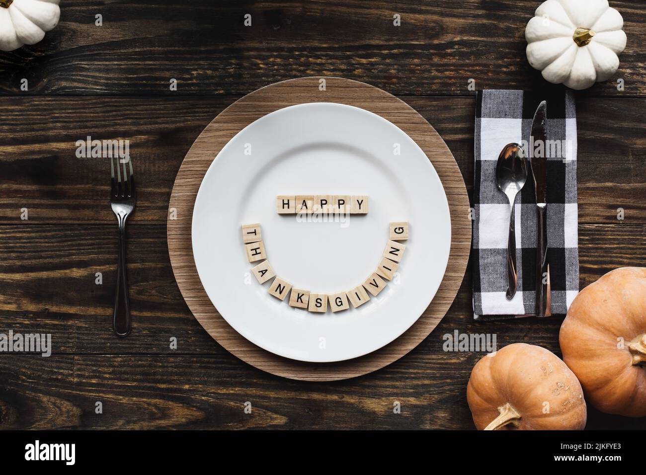 Place setting with plate, napkin, on a  decorated table shot from flat lay or top view position. Happy Thanksgiving Day spelled out with wood block le Stock Photo