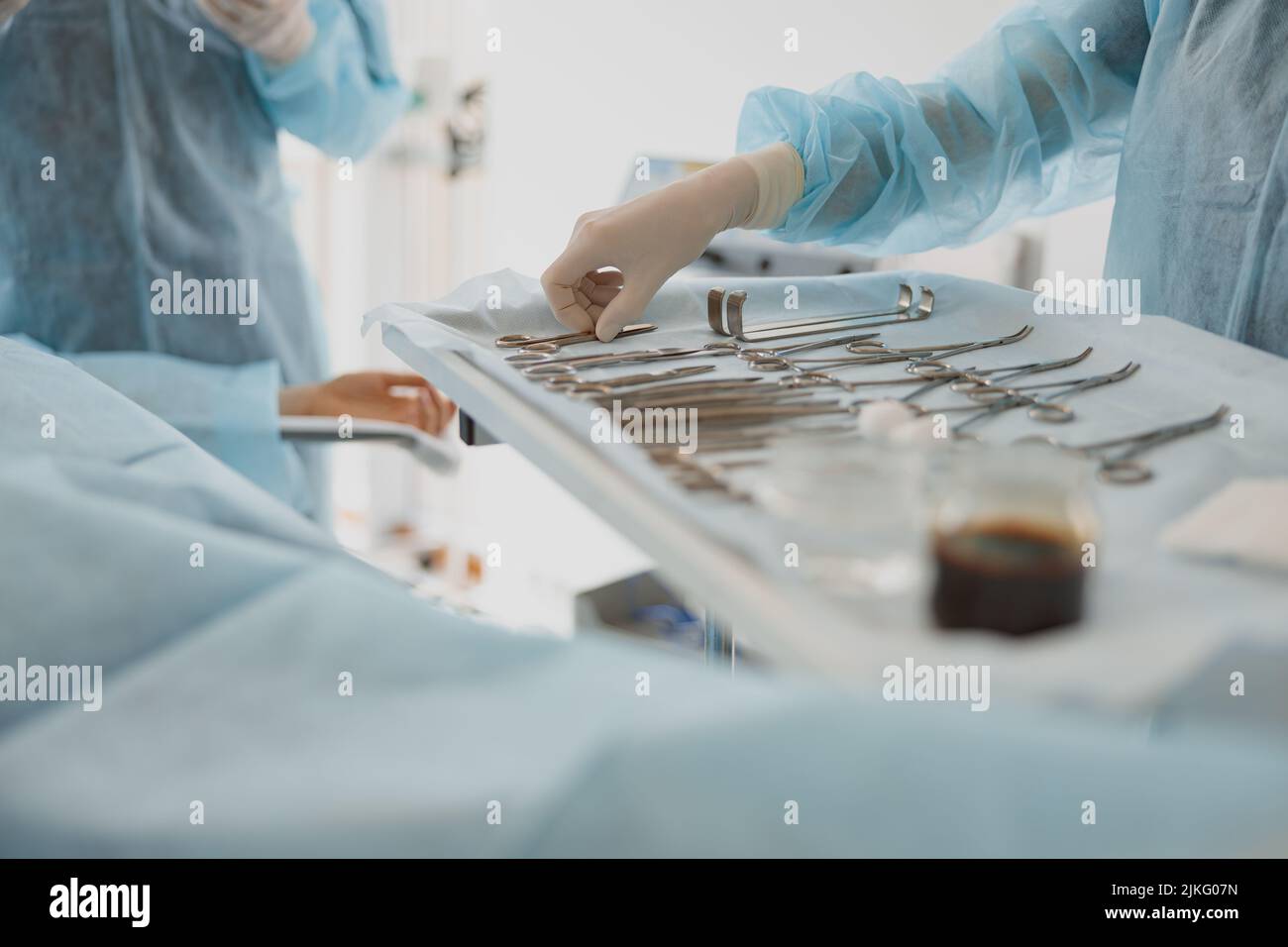 Nurse hand taking surgical instruments from table for a surgery during operation Stock Photo