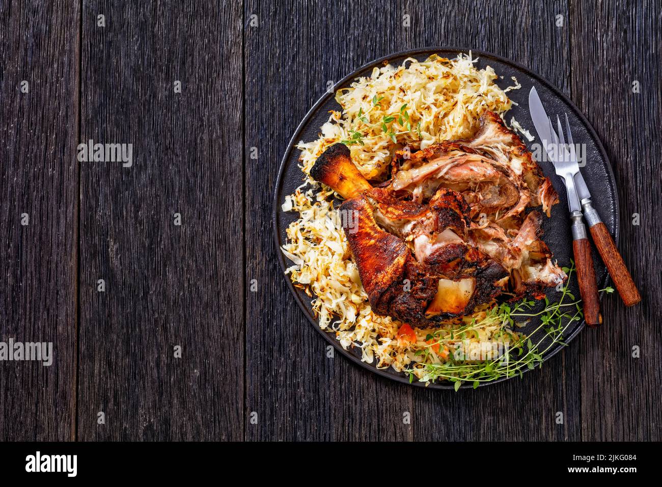 Crispy German Pork Knuckle, roast ham hock, Schweinshaxe, with sauerkraut on black platter with