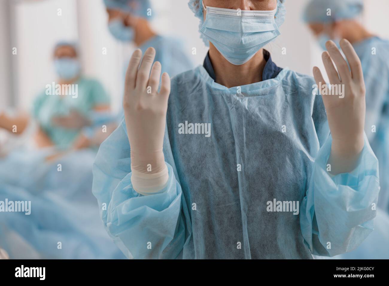 Close up of female surgeon in mask and gloves standing in operating room, ready to work on patient Stock Photo