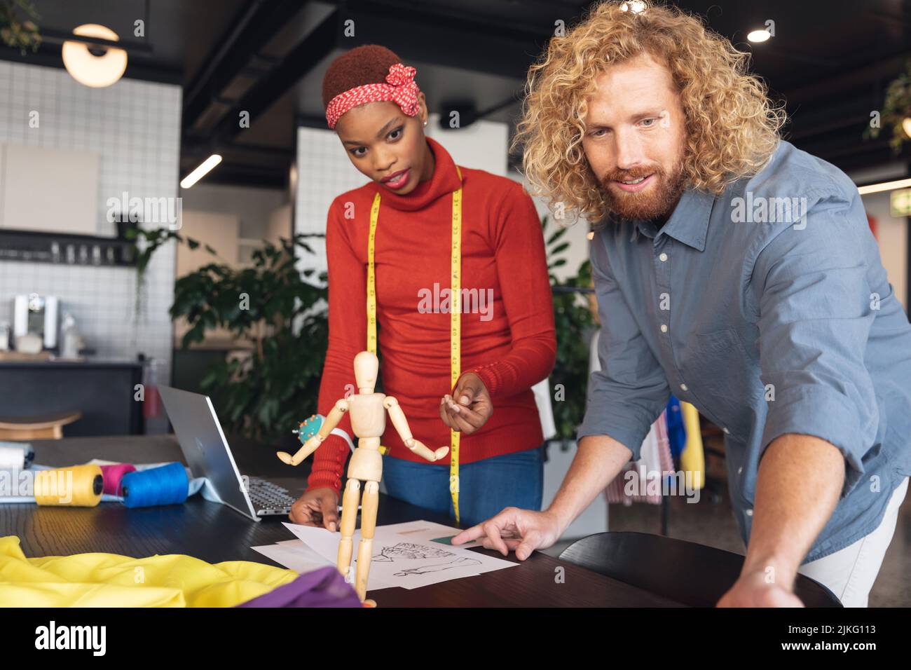 Multiracial male and female fashion designers discussing at desk in ...