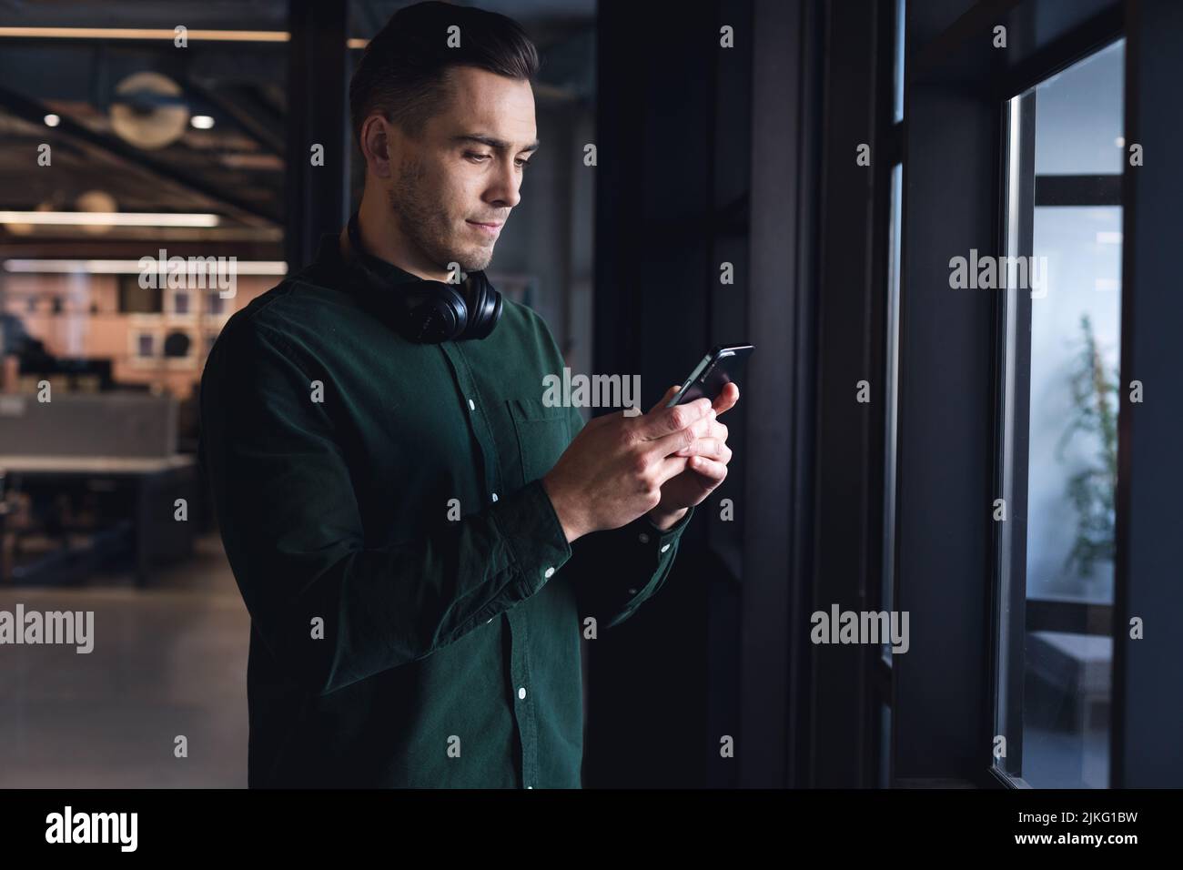 Caucasian young businessman text messaging through mobile phone in creative office Stock Photo