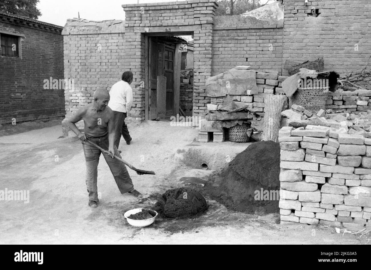 CHINA XIAN man mix clay to cast bricks at small business Stock Photo