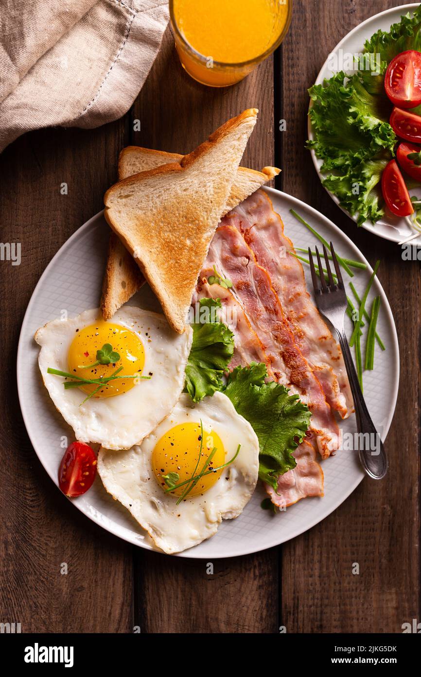 American breakfast with eggs and bacon in a plate on a wooden table. Top view of healthy food Stock Photo