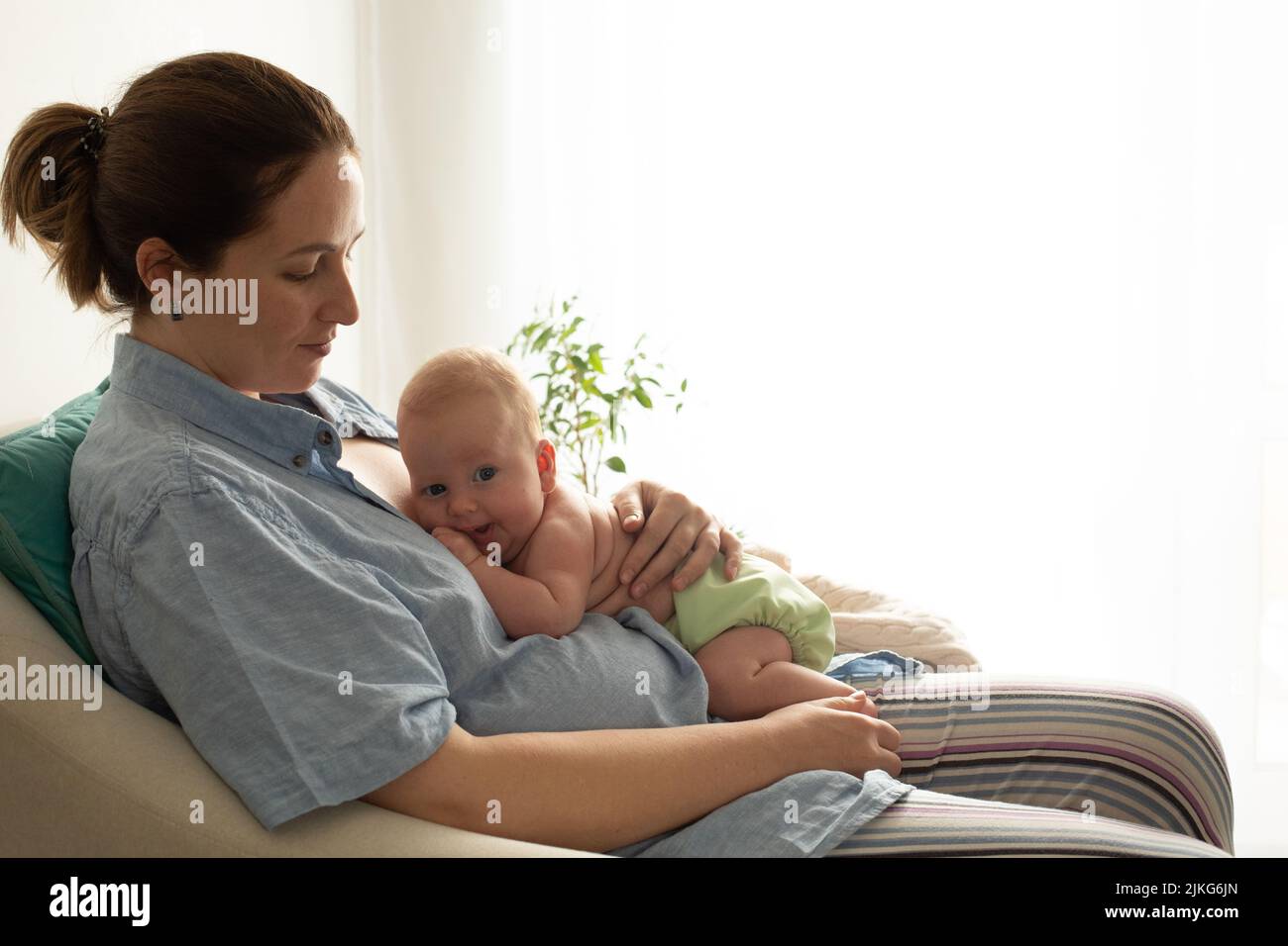 Woman with her baby rest in the chair after breastfeeding Stock Photo
