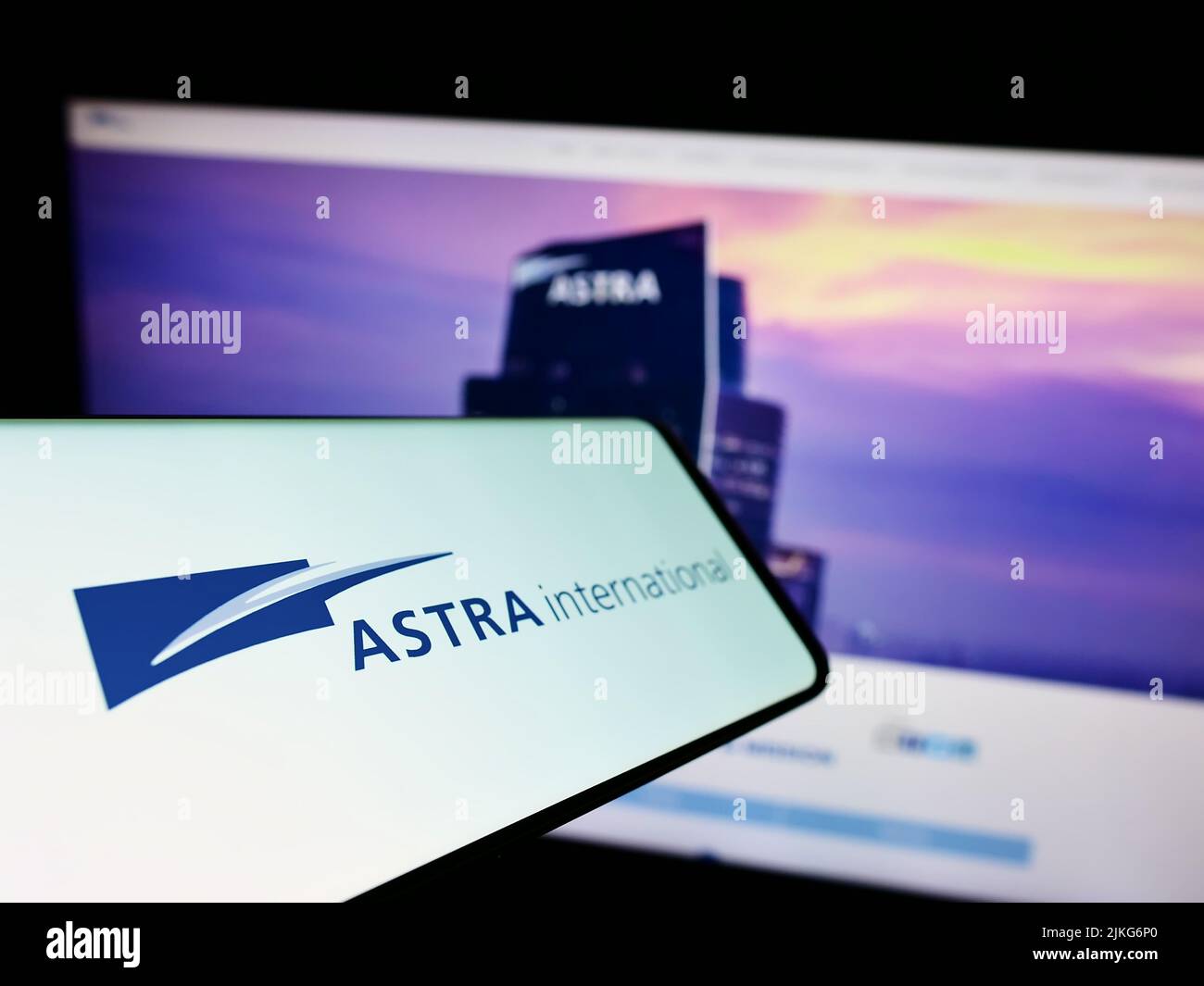 Smartphone with logo of Indonesian company PT Astra International Tbk on screen in front of website. Focus on center-left of phone display. Stock Photo