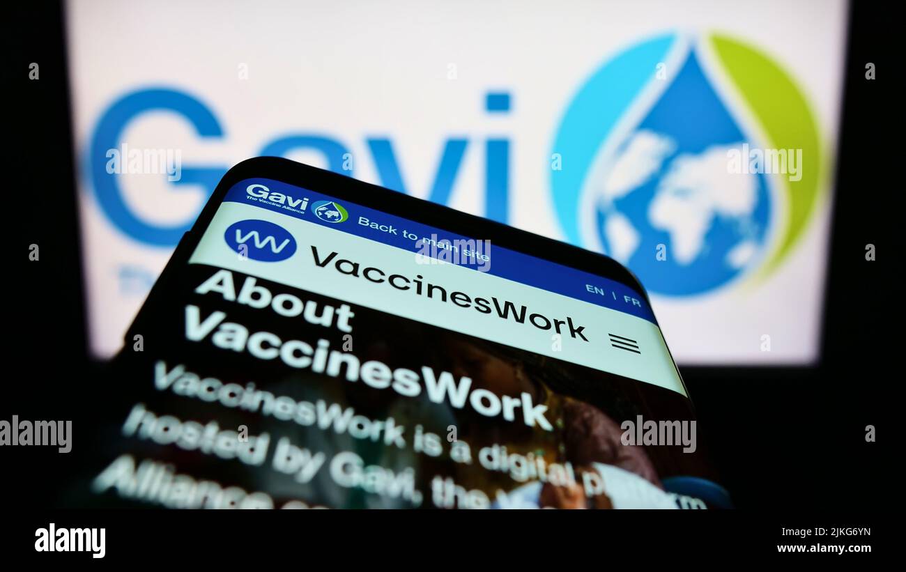 Smartphone with webpage of health partnership Gavi, the Vaccine Alliance on screen in front of business logo. Focus on top-left of phone display. Stock Photo