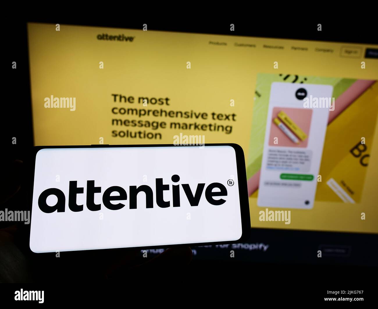 Person holding mobile phone with logo of American marketing company Attentive Mobile Inc. on screen in front of web page. Focus on phone display. Stock Photo