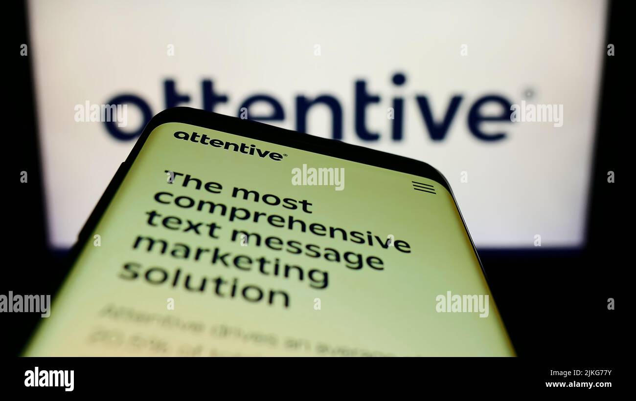 Smartphone with website of US marketing company Attentive Mobile Inc. on screen in front of business logo. Focus on top-left of phone display. Stock Photo