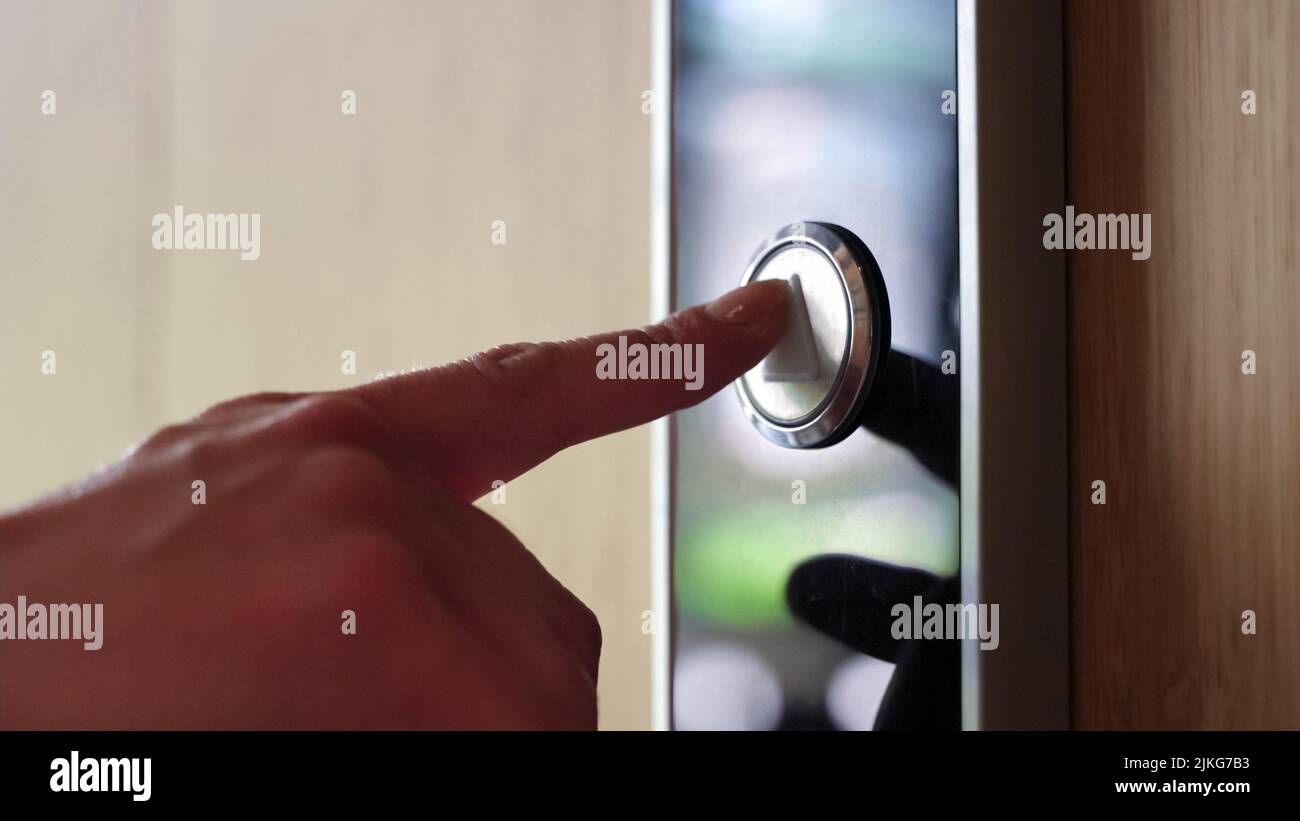 Close-up view on female hand pushing elevator lift button in business center. Stock Photo