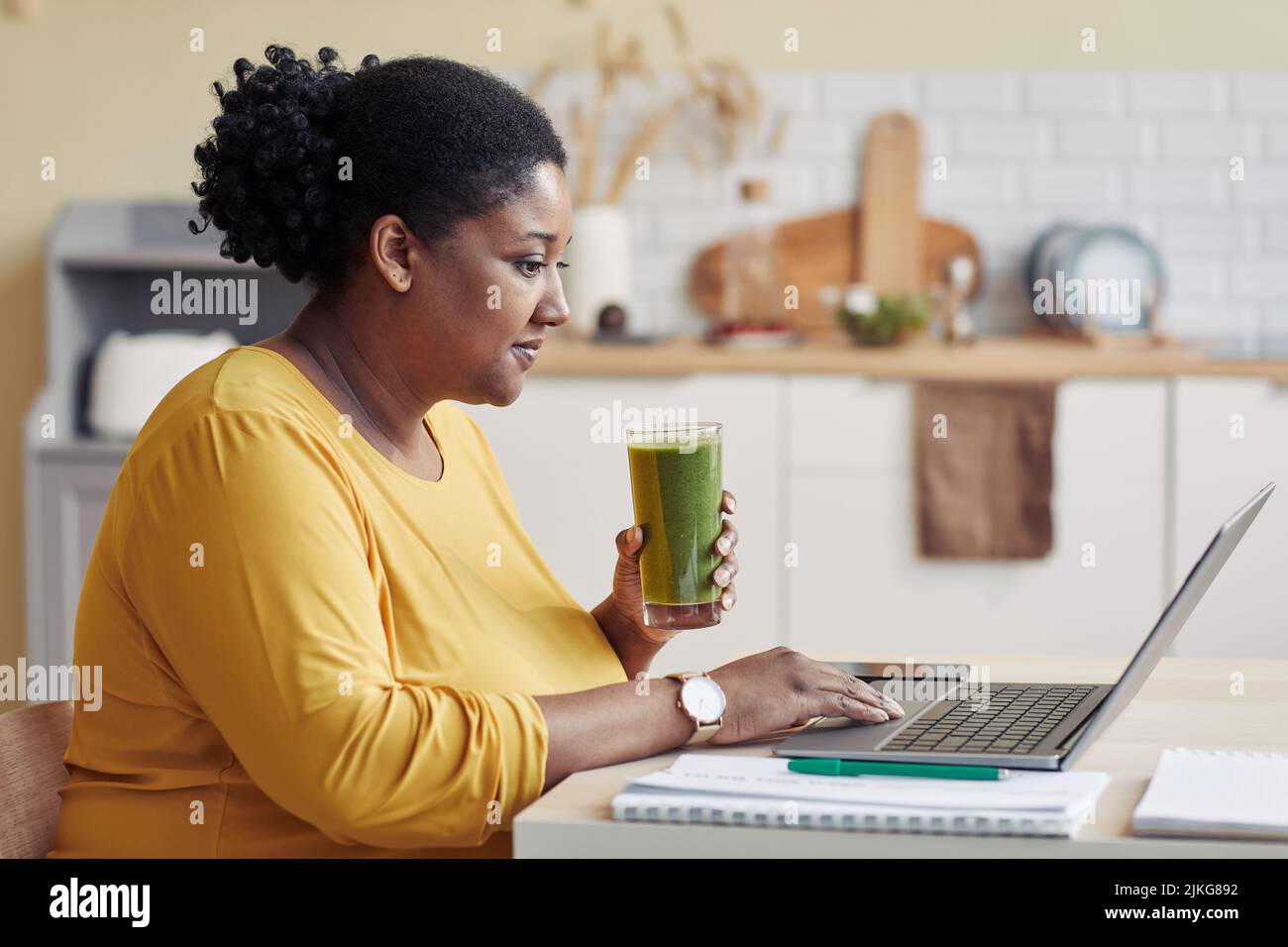 Portrait of smiling black woman drinking smoothie side view Stock Photo