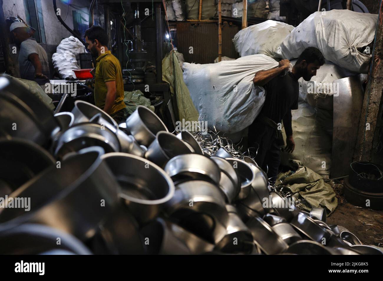 A worker carries a sack full of kitchen utensils inside a factory in Dhaka, Bangladesh August 2, 2022. REUTERS/Mohammad Ponir Hossain Stock Photo